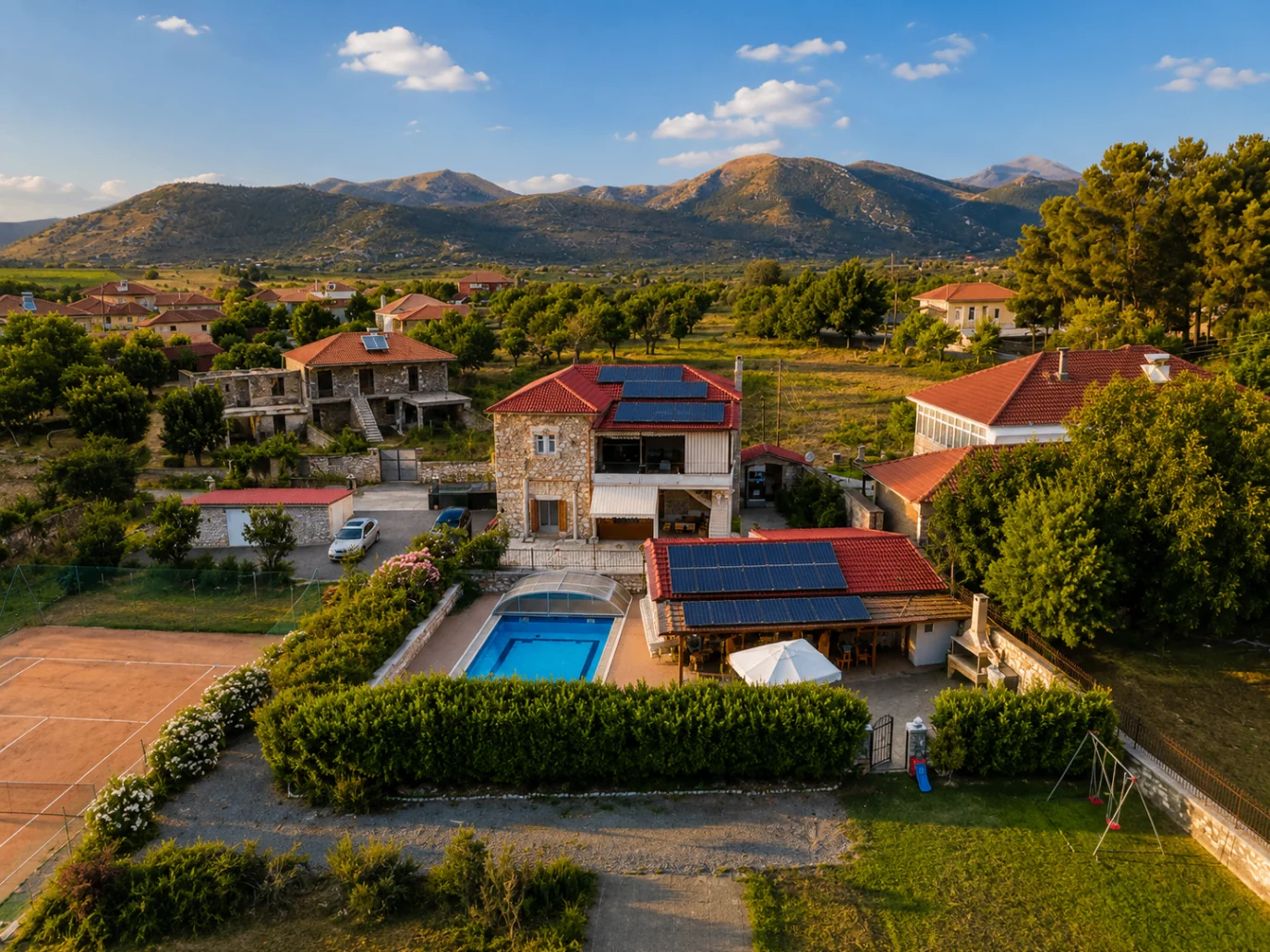 Villa Arcadia exterior with pool, tennis court and mountain backdrop A wide exterior view of Villa Arcadia with the pool, tennis court and mountains behind the property