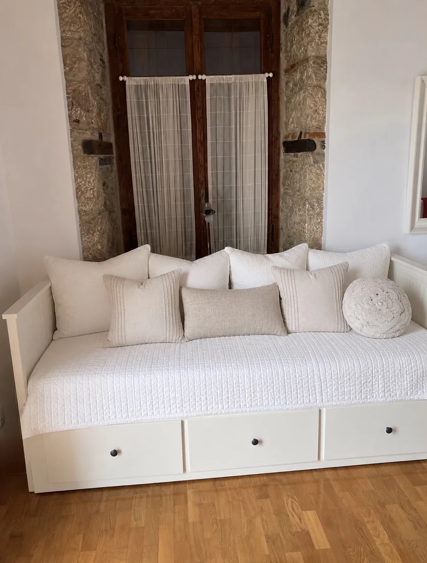 Bright guest room daybed at Villa Arcadia White daybed with neutral cushions in a bright guest room at Villa Arcadia
