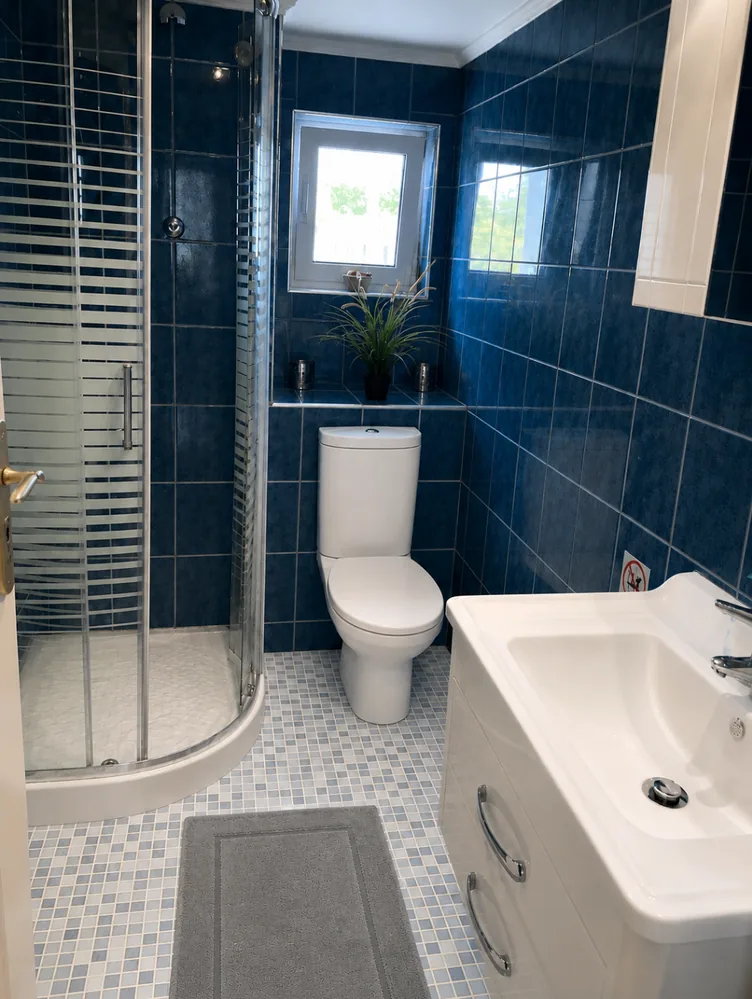 Blue-tiled bathroom at Villa Arcadia Blue-tiled bathroom with shower, sink and window at Villa Arcadia