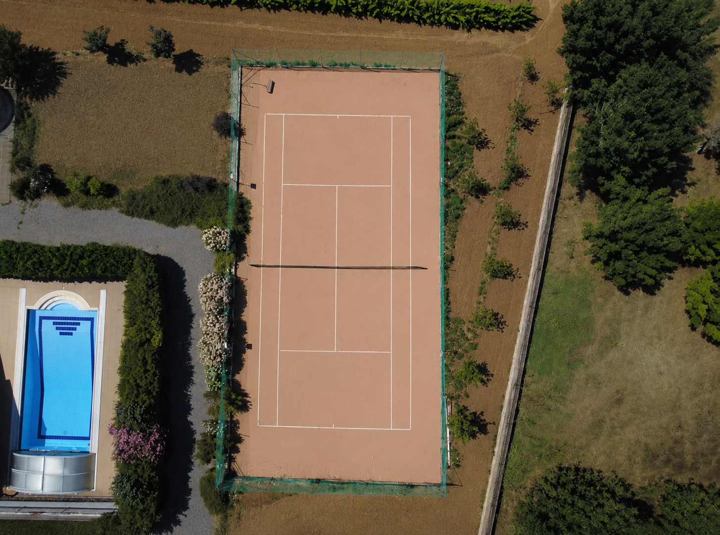 Private tennis court at Villa Arcadia Overhead drone view of the private clay tennis court at Villa Arcadia next to the pool