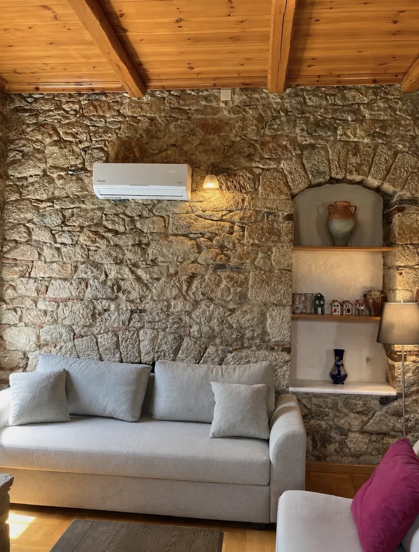 Living room with stone wall at Villa Arcadia Living room sofa against a warm stone wall inside Villa Arcadia